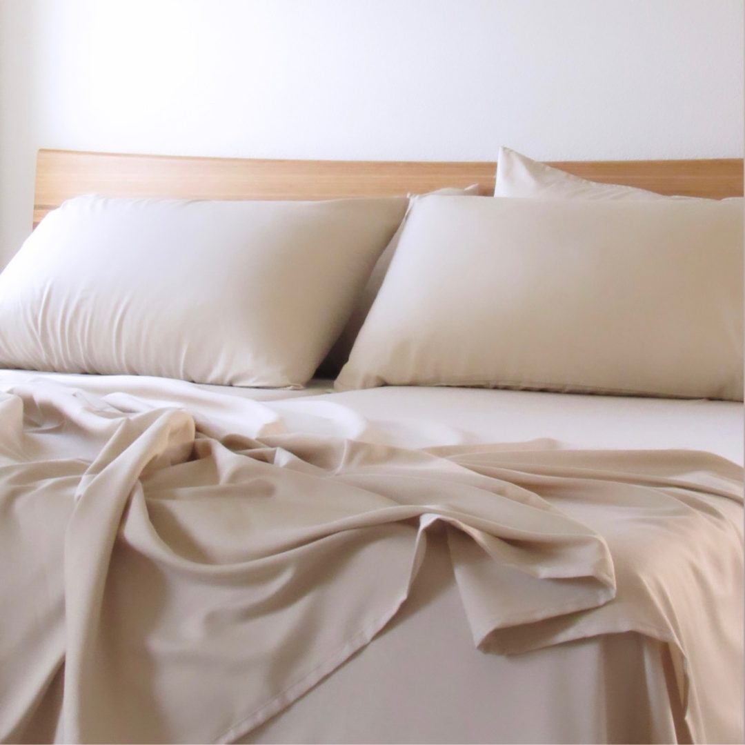 Light beige Copper Infused Bamboo Pillowcase Set on a bed with wooden headboard.